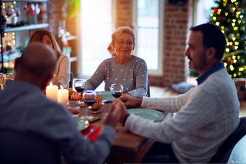 Family and friends dining at home celebrating christmas eve with traditional food and decoration, all sitting on the table together