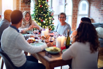 Family and friends dining at home celebrating christmas eve with traditional food and decoration, all sitting on the table together