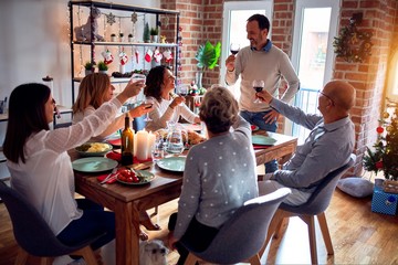 Family and friends dining at home celebrating christmas eve with traditional food and decoration, making a toast for new year best wishes