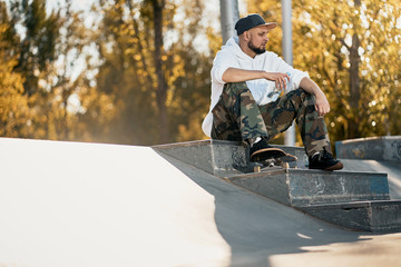 Man in skatepark with skateboard on warm autumn day