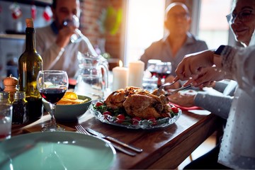 Family and friends dining at home celebrating christmas eve with traditional food and decoration, preparing turkey for dinner