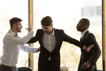 Male colleague set apart angry diverse businessmen fighting in office - obrazy, fototapety, plakaty