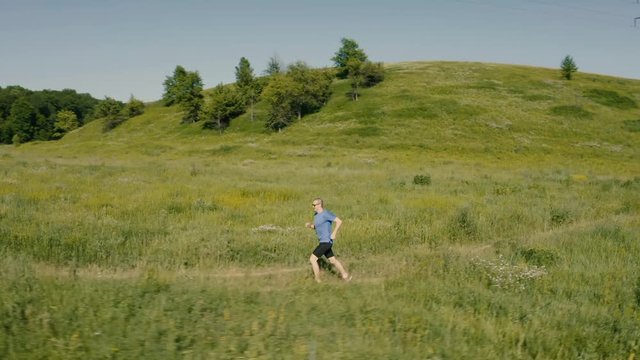 Man runner run outdoor in the field. Airial video from drone.