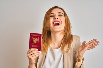 Redhead caucasian business woman holding passport of Russia over isolated background very happy and excited, winner expression celebrating victory screaming with big smile and raised hands