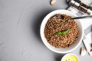 Flat lay composition with bowl of buckwheat porridge served on grey table. Space for text