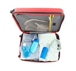 Packed suitcase with deodorant and clothes on white background, top view