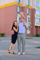 Obraz premium Happy family is standing near their modern house, smiling and looking at camera.
