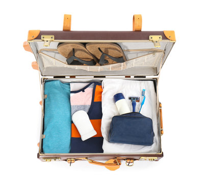 Packed suitcase with deodorants and clothes on white background, top view