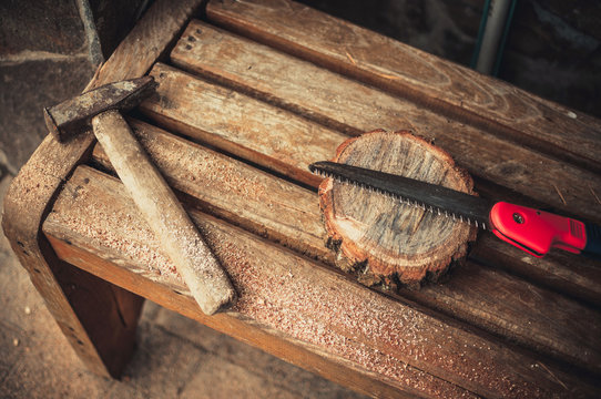 an old hammer, a hand saw and a round bar of pine with sawdust on a bench. Wooden stand for food for the master class. DIY concept.