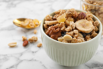 Bowl with healthy granola on white marble table, space for text