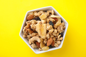 Bowl with healthy granola on yellow background, top view
