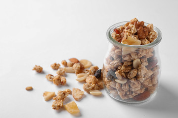 Jar of tasty homemade granola on white background. Healthy breakfast