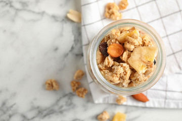 Tasty homemade granola on white marble table, flat lay with space for text. Healthy breakfast