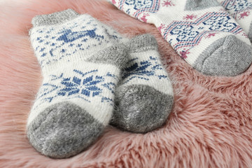 Fototapeta na wymiar Knitted socks on pink faux fur, closeup