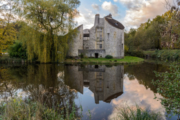 MONTMORENCY, FRANCE - NOVEMBER 10, 2013: The hunting Castle ("Château de la chasse" in french) reflecting on a pond at sunset, located in the Montmorency Forest.