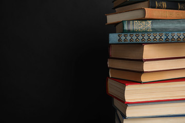 Stack of hardcover books on black background. Space for text