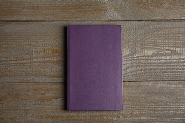Hardcover book on wooden table, top view. Space for text