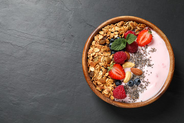 Healthy homemade granola with yogurt on dark grey table, top view. Space for text