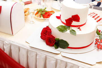 cutting wedding cake decorated with roses