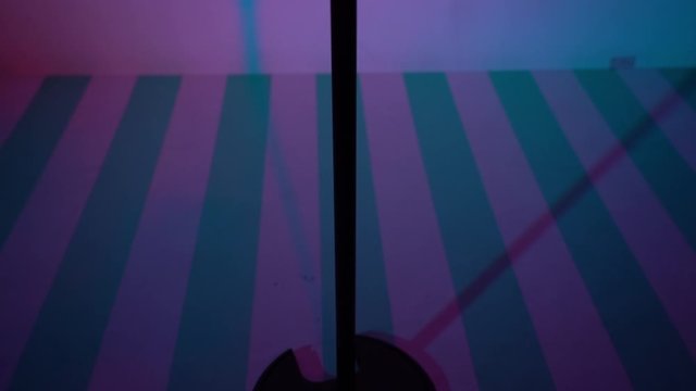 Concert vintage glare microphone for record or speak to audience on stand in dark empty retro club close up. Violet and blue spotlights shine on chrome mic on purple background. The camera moves up.