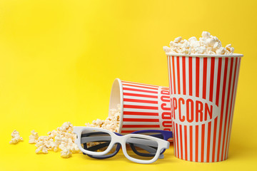 3D glasses and popcorn on yellow background, space for text. Cinema snack