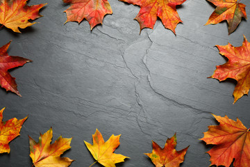 Frame made of autumn leaves on grey stone table, flat lay. Space for text