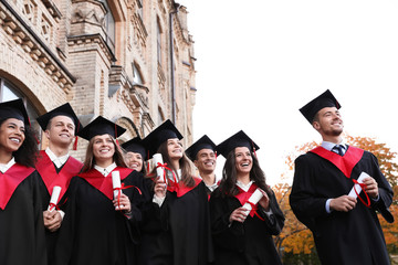 Happy students with diplomas outdoors. Graduation ceremony