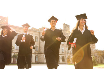Happy students with diplomas outdoors. Graduation ceremony