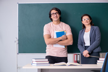 Old female teacher and male student in the classroom