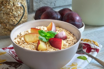 Sweet delicious healthy breakfast. Porridge with plums on the kitchen table.