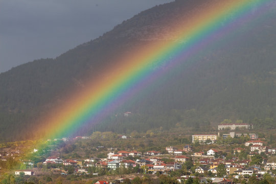 Regenbogen über einem kleinen Ort im Gebirge