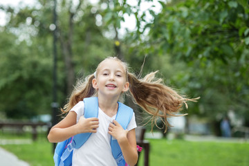 Child girl runs and smiles. Schoolgirl with backpack. The concept of school, study, education, friendship.