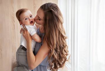 Happy family. Close up portrait of young attractive mother holding baby in her arms and gently...