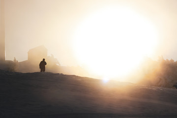 A man goes to the house and around the snow and the setting sun shines very low. Crimean mountains in winter