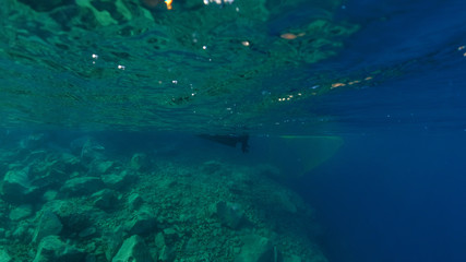 Underwater and sea level photo of fisherman in bay of Ammoudi below famous village of Oia, Santorini island, Cyclades, Greece