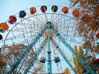 Ferris wheel in city park, bottom view of multicolored cabins 
