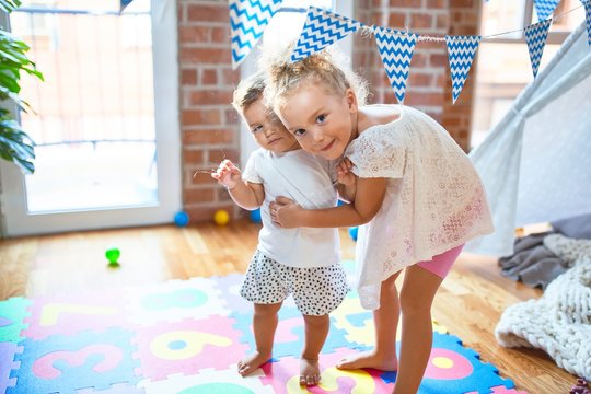 Beautiful toddlers smiling happy standing around lots of toys at kindergarten