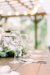 Rustic table setting with floral decorations, lanterns. Wineglasses on the table. Wedding or dinner table in restaurant outdoors