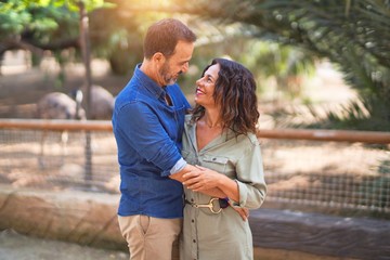 Middle age beautiful couple smiling happy and confident at town park. Standing with smile on face and hugging