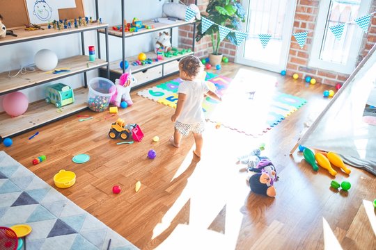 Adorable toddler playing around lots of toys at kindergarten