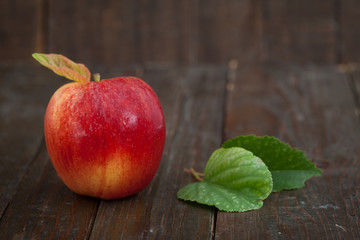 Fresh, red apple with leaves on wooden background. Organic apple, sweet and healthy fruit.