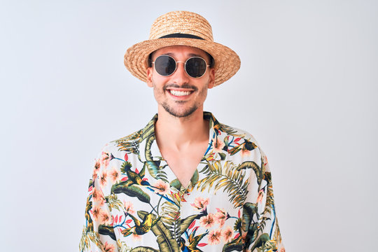 Young handsome man wearing Hawaiian shirt and summer hat over isolated background with a happy and cool smile on face. Lucky person.