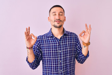 Fototapeta premium Young handsome man standing over isolated background relax and smiling with eyes closed doing meditation gesture with fingers. Yoga concept.