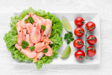 tasty cooked shrimps with tomato and lime on wooden table