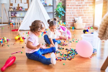 Adorable toddlers playing with building blocks toy at kindergarten