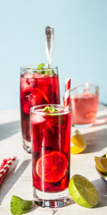 Tea with hibiscus, berries (raspberries and blackberries), mint, lime, lemon and ice in the sun with shadow. Trendy style with artistic shadows.