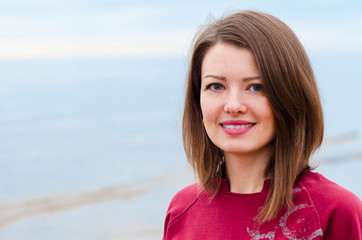 portrait of a young happy girl with a beautiful smile on the seashore outdoors.