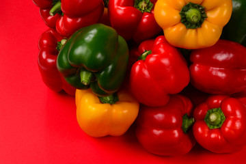 Fresh red, yelow, green bell pepper on a red background.