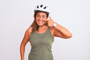 Middle age mature cyclist woman wearing safety helmet over isolated background Pointing with hand finger to face and nose, smiling cheerful. Beauty concept