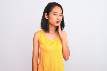 Young chinese woman wearing yellow casual t-shirt standing over isolated white background touching mouth with hand with painful expression because of toothache or dental illness on teeth.